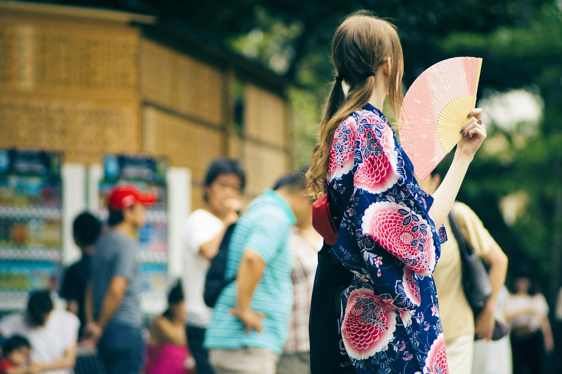 Femme en yukata tenant un éventail au bord d'une route