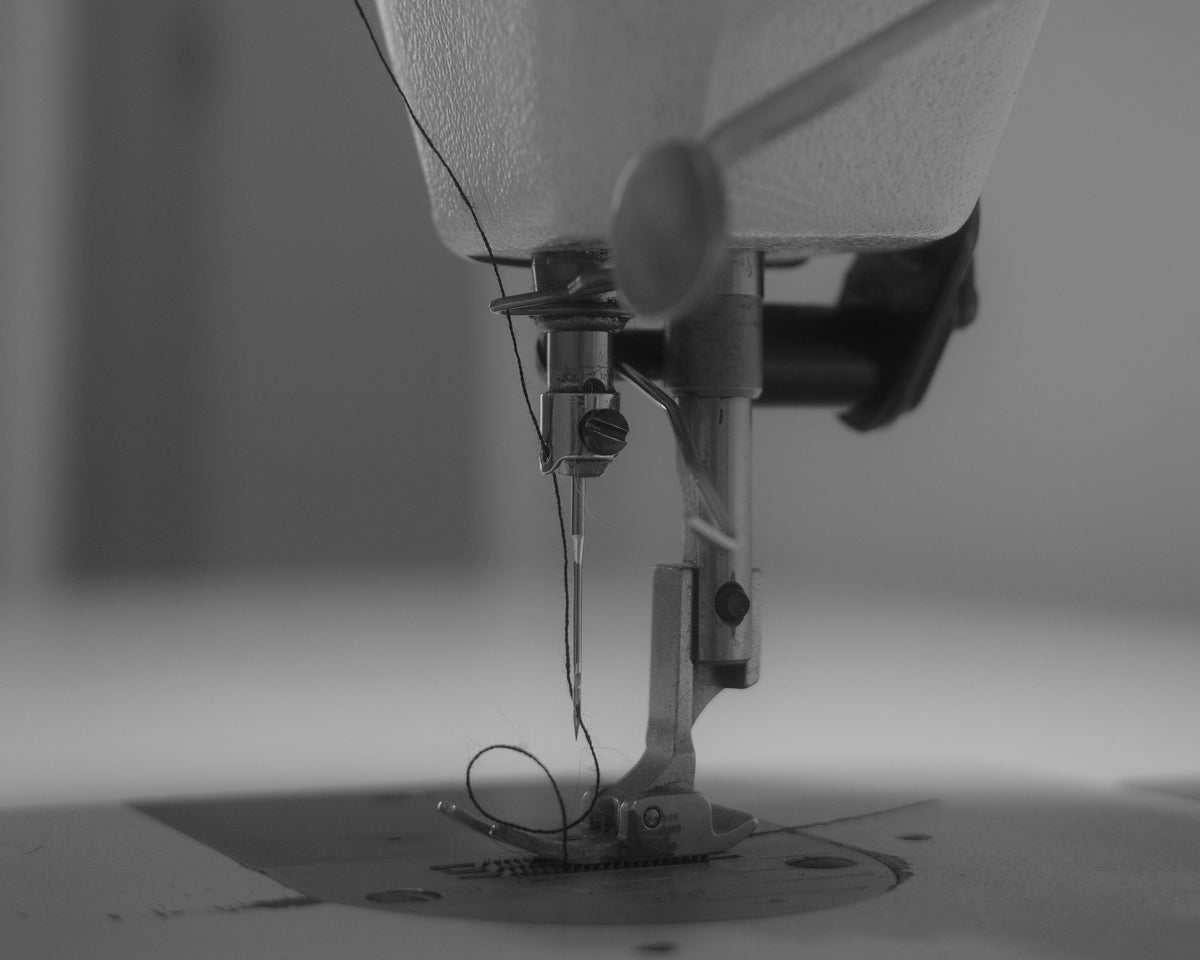 Aiguille d'une machine à coudre piquant un tissu, en noir et blanc
