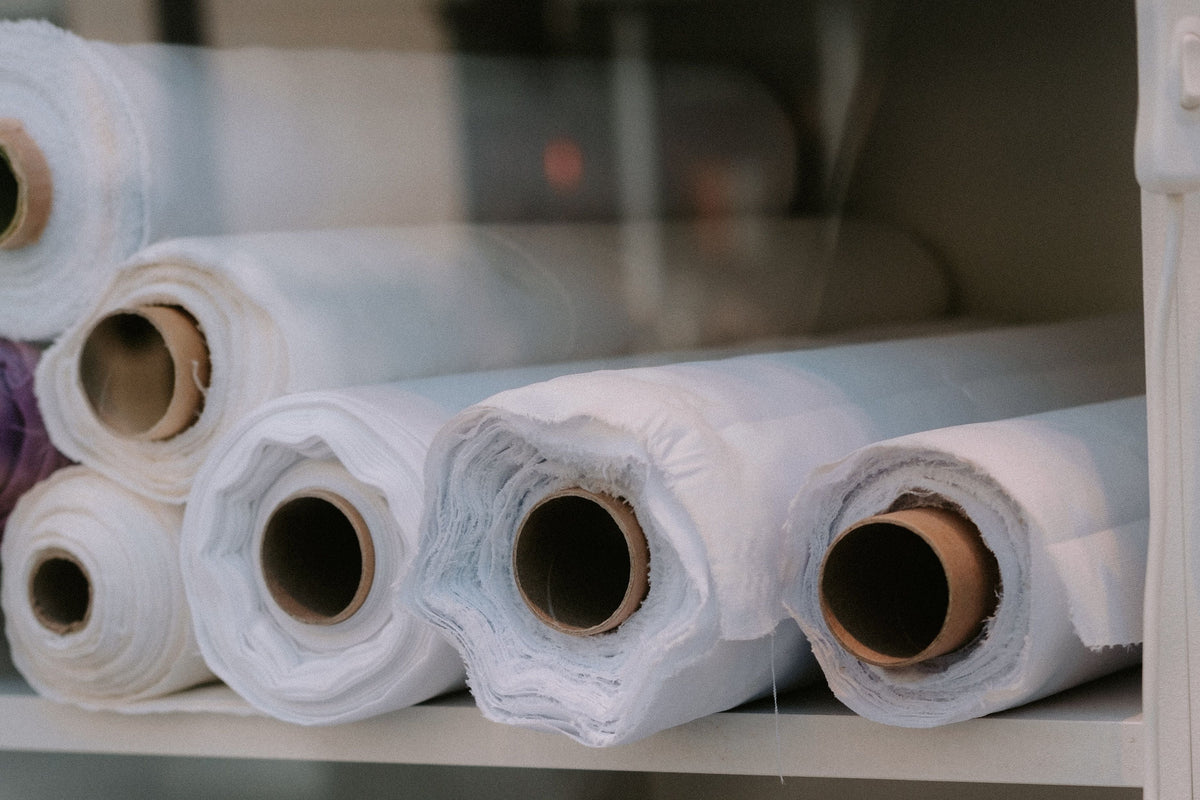 Rouleaux de tissu en coton blanc rangés sur une étagère d'atelier
